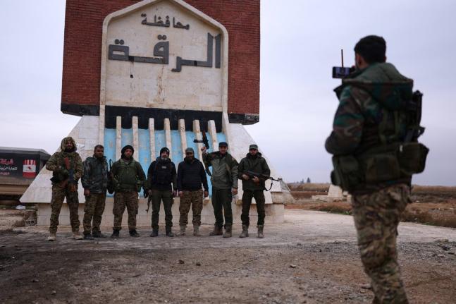 Syrian government soldiers pose for a photo taken by another soldier at the entrance to Raqqa.