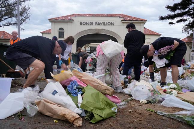Workers gather floral tributes, messages of support and items left as a memorial is dismantled in Sydney, Monday, December 22, 2025, a week after an attack on a Jewish festival that left 15 dead. (AP Photo/Rick Rycroft)