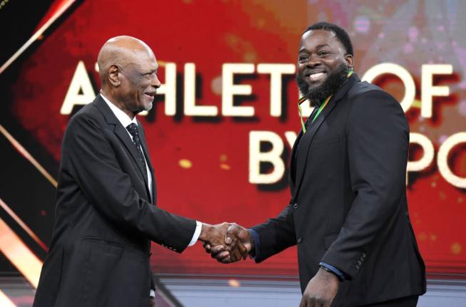 Chad Wright, 2025 Weightlifting Athlete of the Year (right), collects his award at the RJRGLEANER National Sports Award at TVJ Studios on Sunday from George Campbell, General Manager, Coldfield Manufacturing/Pure Country.