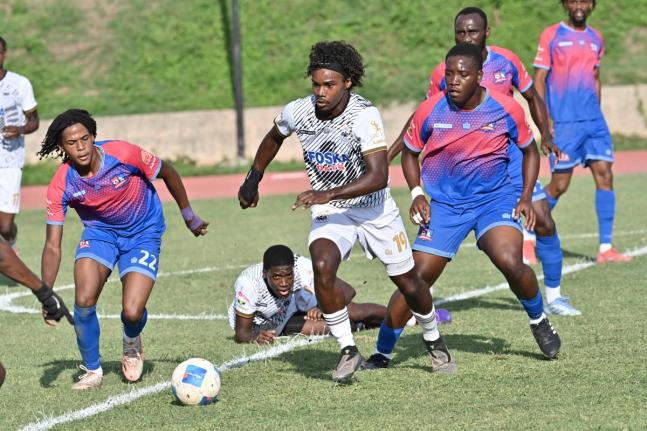 Cavalier’s Chad James sprints away from a mid-pitch melee with Dunbeholden’s Nathaniel Taj Waul (left) and teammate Christopher Matthews in chase during yesterday’s Jamaica Premier League game at Stadium East. Cavalier won 5-1.