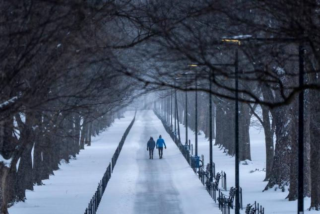 Two people walk along the National Mall as snow falls on January 25, 2026, in Washington. 
