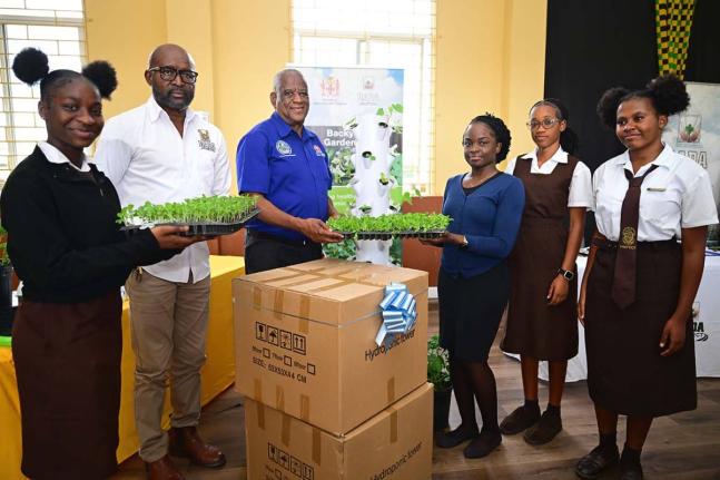 Minister of State in the Ministry of Agriculture, Fisheries and Mining, Franklyn Witter (third left), presents a vertical hydroponic tower to agricultural science teacher at Holmwood Technical High School Shania Wright (fourth left) during a ceremony held 