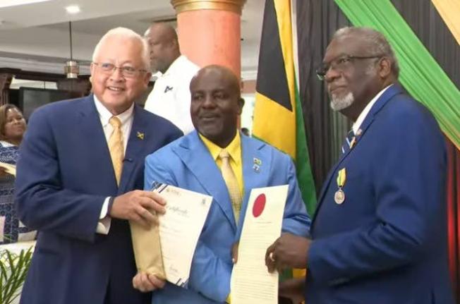 Justice and Constitutional Affairs Minister Delroy Chuck (left) and St James Custos Bishop Conrad Pitkin (right) present the commissioning documents and seal of justice of the peace (JP) to The Gleaner’s Albert Ferguson during a commissioning ceremony fo