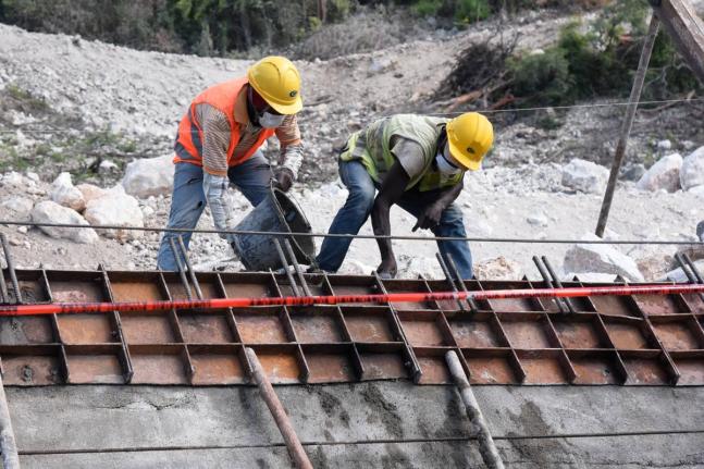 This 2020 photo shows workers pouring concrete in a retaining wall along the St Thomas main road