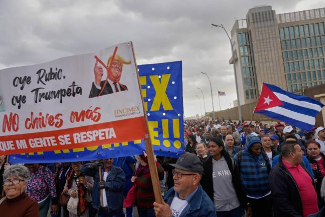 People holding a banner against President Donald Trump, march outside the U.S. Embassy to protest the killing of Cuban officers during the U.S. operation that captured Venezuelan President Nicolas Maduro, in Havana, Cuba, Friday, Jan. 16.