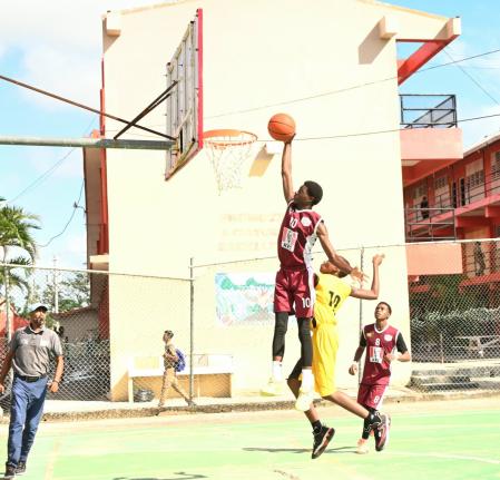 Herbert Morrison Technical High School’s Shamar Russell (left) goes up for a dunk against York Castle High’s J’Dor Griffiths during their ISSA Schoolboy Under-16 Basketball semi-final match at Herbert Morrison Court yesterday