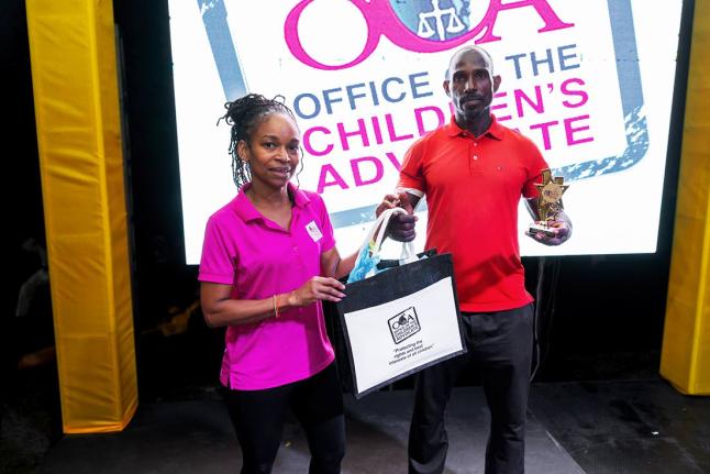 Ann Margaret Lim (left) from the Office of the Children’s Advocate, makes a presentation to Christopher Wilmot, the winner of the Burpees competition, during the 2026 FitFest Party & Expo (New Year Edition) on January 31 at the NWC Sports Club.