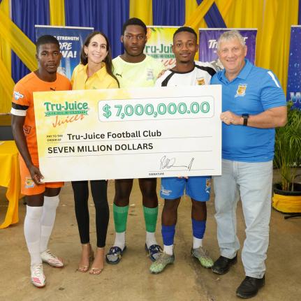Lauren Mahfood, marketing manager at Trade Winds Citrus Limited (second left), and Peter McConnell, managing director of Trade Winds Citrus Limited (right), share a moment with members of the Tru Juice Football Club following the formal handover of $7 mill