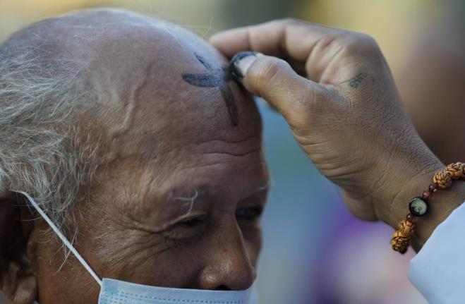 A lay minister places ash on the forehead of a devotee during Ash Wednesday outside a church in downtown Manila, Philippines. 
