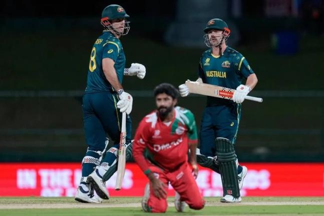 Australia’s Travis Head and captain Mitchell Marsh run between the wickets as Oman’s Jay Odedra (centre) dives to field a ball during the T20 World Cup cricket match between Australia and Oman in Pallekele, Sri Lanka, yesterday.