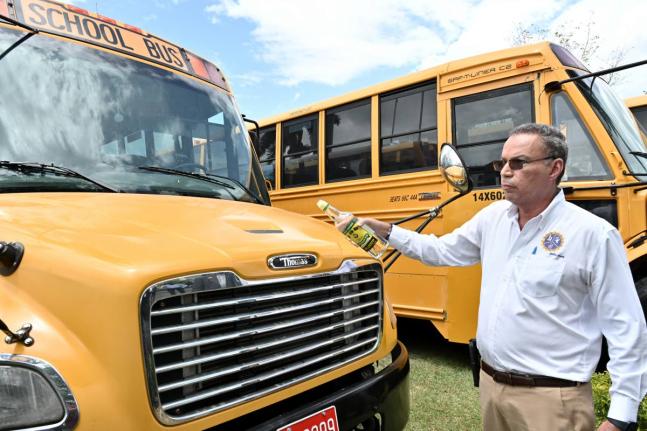 
Transport Minister Daryl Vaz pours rum on one of the buses procured for the rural school bus programme during a blessing ceremony at Jamaica House in St Andrew in August 2025.