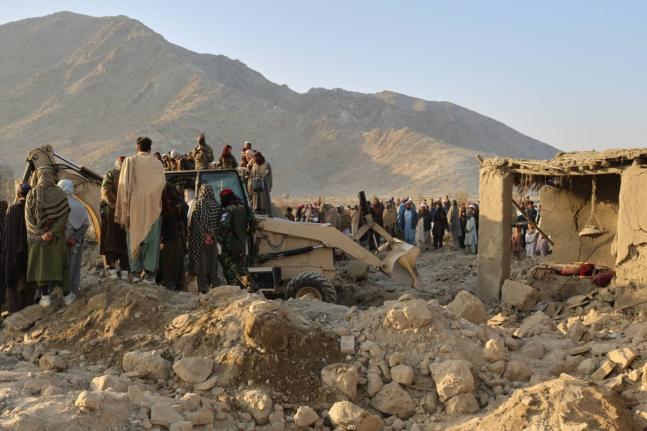 Local residents and civil defense workers look on as a bulldozer clears the rubble of a house hit by a cross-border Pakistani army strike in the Behsud district of Nangarhar province, Afghanistan, on February 22, 2026. 
