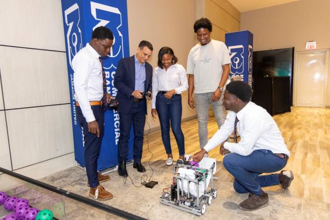 From left: Romario Lindo, captain of St Mary’s Technical High School; Andrew Pearman, director, NCB Foundation; and coaches Tashiba Julius and Gavin O’Meally test the team’s robot, ‘Small Fry’, under the guidance of Ackeem Gordon, sixth form stud
