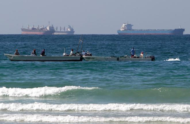 Fishermen working in front of oil tankers south of the Strait of Hormuz on January 19, 2012, offshore the town of Ras Al Khaimah in United Arab Emirates. 