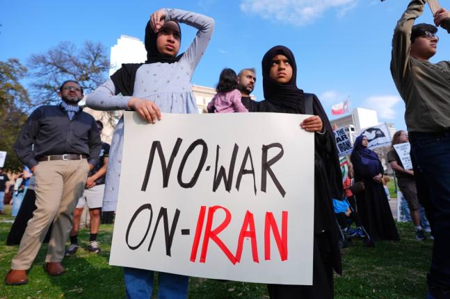 Children hold a sign protesting war against Iran during an antiwar demonstration at Dealey Plaza in downtown Dallas.