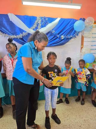 Colleen Wint-Bond, project coordinator at the Violence Prevention Alliance, presents gifts to a student at the Chalky Hill Primary and Infant School on National Peace Day.