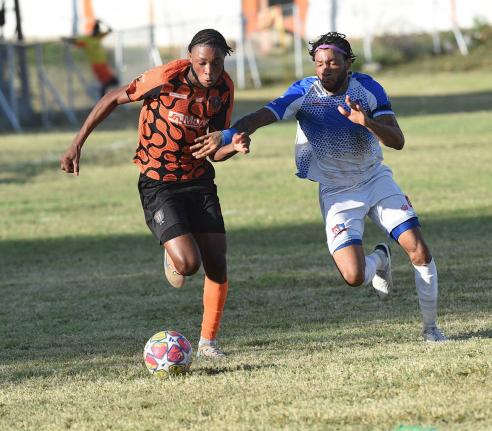 Joshua Dewar (left) of Tivoli Gardens FC dribbles away from Dunbeholden FC’s Odane Samuelsduring their  Jamaica Premier League match at the Edward Seaga Sports Complex yesterday.