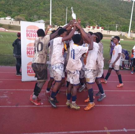 Jamaica College’s under-16 team celebrates with the Burger King Under-16 football trophy after a 2-1 win over Kingston College at Stadium East yesterday.