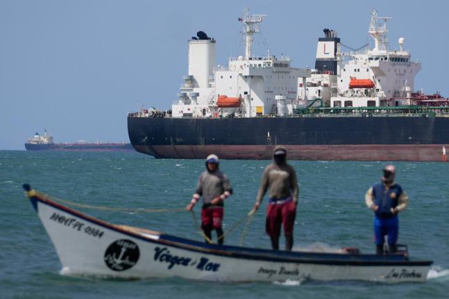 Fishermen pass an oil tanker in the Gulf of Venezuela off the shore of Punta Cardon, Venezuela.