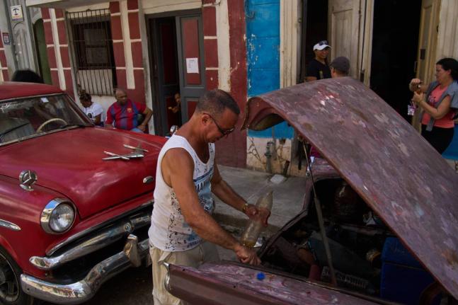A man finishes putting fuel in his car's tank, located in the back of the car, during a blackout in Havana, Cuba, Monday, March 16, 2026. (AP Photo/Ramon Espinosa)