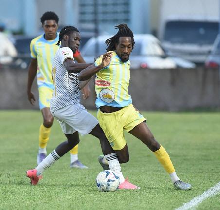 Jerome McLeary (centre) of Cavalier  challenges Waterhouse’s Omani Leacock during their Jamaica Premier League match at the Drewsland Mini Stadium yesterday. Home team Waterhouse won the game 2-1. 
