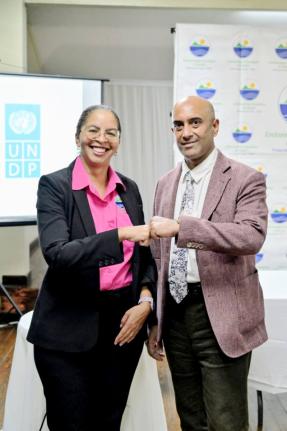 Nicole Adamson, CEO of the Environmental Foundation of Jamaica (EFJ) (left), and Dr. Kishan Khoday, Resident Representative of the UNDP Multi Country Office in Jamaica, share a fist bump after signing a Memorandum of Understanding to scale up climate‑act