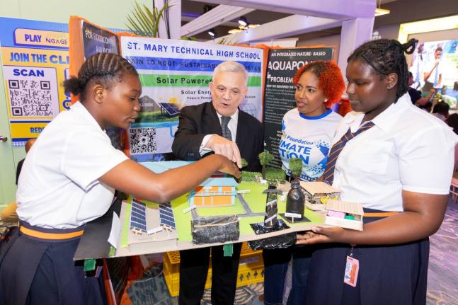 Damian Obiglio (second left), chairman of the JPS Foundation, and Sophia Lewis (second right), head of the JPS Foundation, engage with Abigail Dixon (left) and Ajada Duffus of St Mary Technical High School as they present their solar-powered hydroponics an