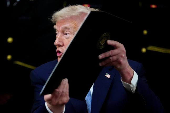 AP 
President Donald Trump holds up an executive order after signing it during the Commander-in-Chief’s Trophy presentation with the Navy Midshipmen football team in the East Room of the White House, Friday, March 20, 2026, in Washington. 