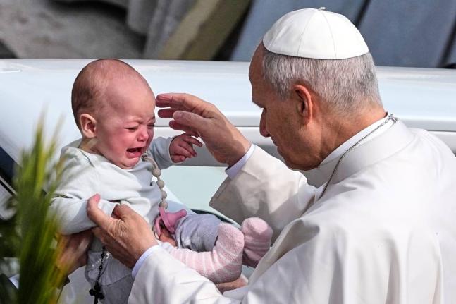 Pope Leo XIV caresses a child after presiding over Mass in St Peter’s Square at the Vatican on the Catholic feast of Palm Sunday.