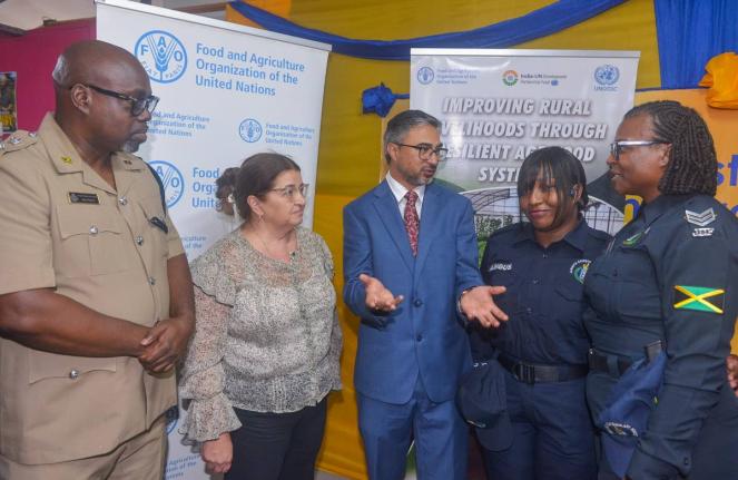 Indian High Commissioner to Jamaica, His Excellency Mayank Joshi (centre), makes a point to Head of the Guanaboa Vale Police, Sergeant Navelette Davis-Leachman (right), and Constable Leonie Angus (second right), during the recent certification ceremony for