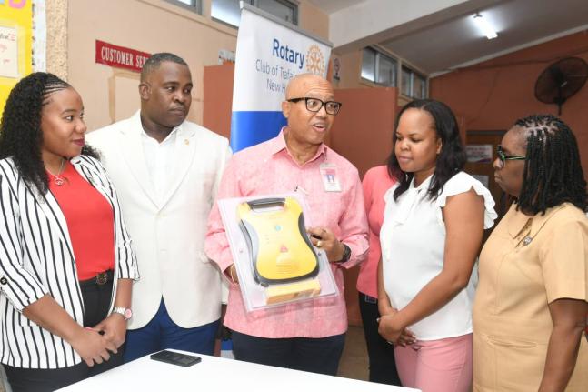 Professor William ‘Bill’ Aiken (centre), district governor for Rotary District 7020, explains how the defibrillator should be used to Dr Wendy-Ann Byfield-Lyons (second from right), medical officer in charge of the Duhaney Park Health Centre in St Andr
