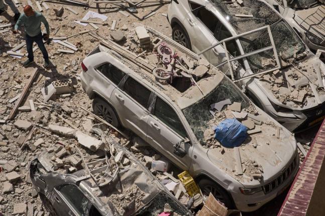 A man inspects the damage to cars and an apartment building struck by an Iranian missile in Ramat Gan, Israel on April 6, 2026. (AP Photo/Oded Balilty)