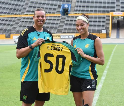 Hubert Busby (left), head coach of the Reggae Girlz, presents defender Chantelle Swaby with a jersey ahead of her 50th game for the national team. 