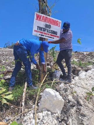 Representatives from SCJ Holdings Limited erect a 'No Trespassing' sign on former sugar lands in Trelawny as part of measures to stem the illegal occupation and unauthorised sale of such properties across the island.