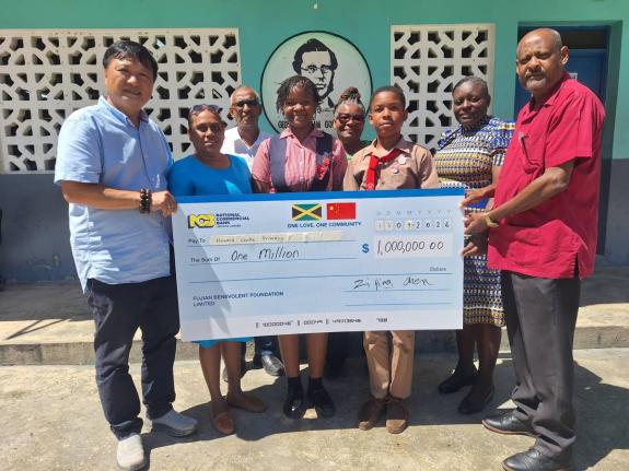 Ziping Chen (left), chairman of LCH Development Limited, presents a cheque valued at $1 million from the Chinese Community in Montego Bay to Dave Scott (right), principal of Howard Cooke Primary School. Sharing in the occasion are (from second left) Veroni