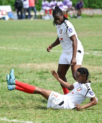 Arnett Gardens’ Shikira Douglas falls to the ground after scoring her fourth goal in a Jamaica Women’s Premier League encounter against Real Mona at the Alpha Institute on Saturday. Looking on is teammate Tasheka Reid.