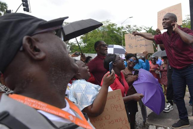 Dennis Samuels (right), Union Representative at the University of the West Indies (UWI), addresses employees at both the University of the West Indies (UWI) and University Hospital of the West Indies (UHWI) who demonstrated outside the gates of the UWI for