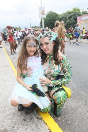 Eight-year-old Tessa Tupicov (left) and her sister, Scarlett Tupicov, pose for the camera during the Yard Mas Road March on Sunday. 
