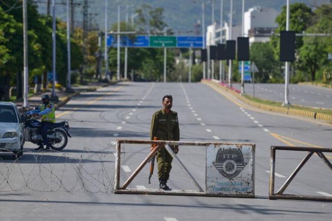 A police officer stands guard at a checkpoint on a barricaded road to ensure security ahead of the second round of the US Iran officials talks, in Islamabad, Pakistan, Sunday, April 19, 2026. (AP Photo/M.A. Sheikh)