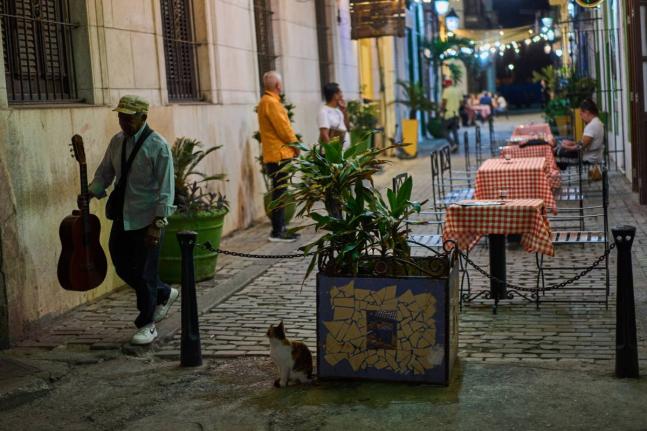 A street musician walks past a restaurant in Havana.