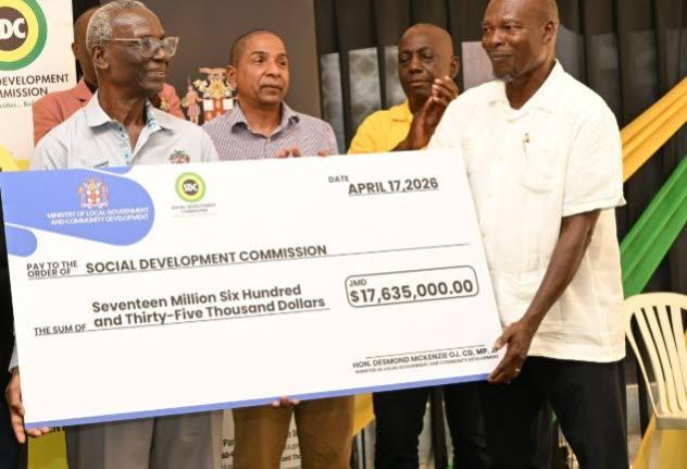 Minister of Local Government and Community Development, Desmond McKenzie (left), makes a symbolic handover of a cheque under the Government's Community Church Clean-Up and Restoration Initiative that was accepted by Reverend Othniel Watson (right) of the M