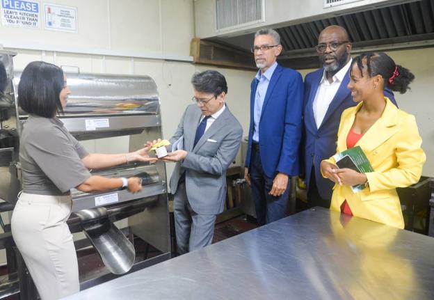 Founder of Mel’s Sticky Jams Limited, Melissa Tavares-Wilson (left), presents Ambassador of Japan to Jamaica, Kohei Maruyama, with one of her pineapple and ginger flavoured jams during a tour of the agro-processing area located at the Jamaica Business De