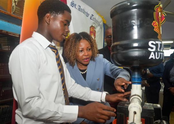 Minister of Education, Skills, Youth and Information, Senator Dr Dana Morris Dixon (second left), examines an automatic chicken feeder made by students of St Andrew Technical High School, during an alumni engagement visit on April 14, in commemoration of t