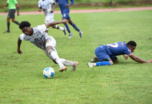 Cavalier FC’s Kimarly Scott dribbles away from Spaish Town Police’s Adrew Vanzie during their Jamaica Premier League football match at Stadium East yesterday. Cavalier won 3-0.