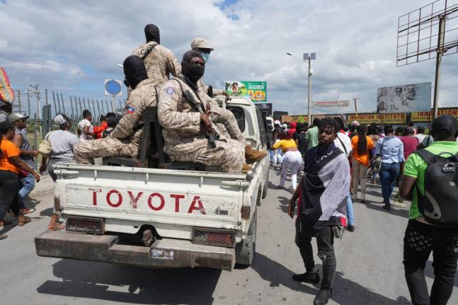 National Police patrol alongside a march by factory workers demanding a salary increase in Port-au-Prince, Haiti, Monday, April 13, 2026. (AP Photo/Odelyn Joseph)