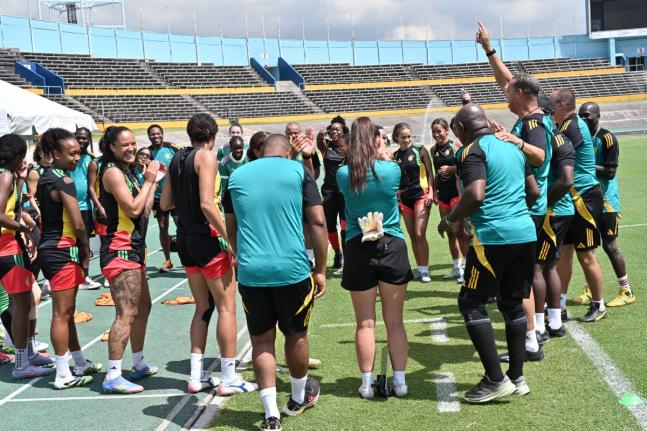 Reggae Girlz coach, Hubert Busby Jr (arm raised) rallies his troops during a training session at the National Stadium on April 17.