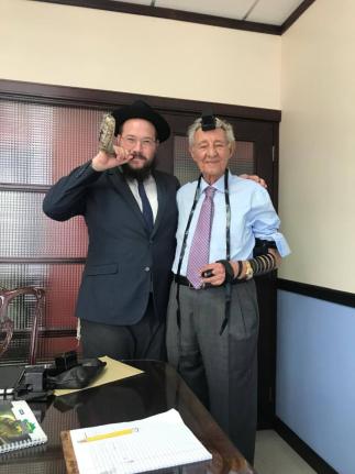 Hugh Hart (right) is seen wearing Tefillin alongside Rabbi Yaakov Raskin, who blows a ram’s horn in honor of the Jewish New Year.