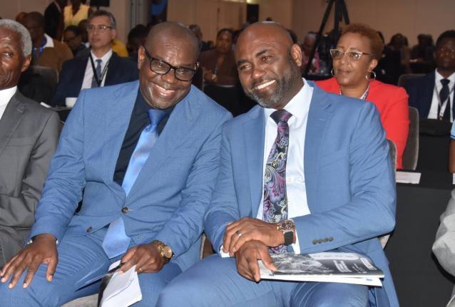 Chairman of the Organisation of Caribbean Utility Regulators, Ansford Hewitt (left), shares a light moment with Dr Andrew Wheatley, minister without portfolio in the Office of the Prime Minister, with responsibility for science, technology and special proj