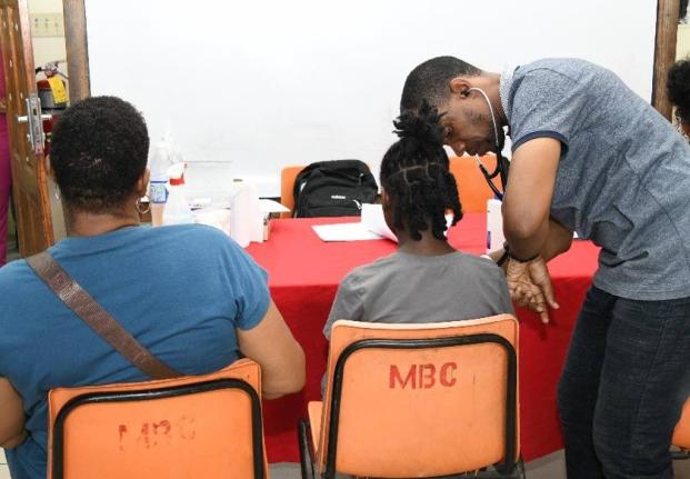 Dr Ryan Haynes, UTech, Jamaica Medical Centre, checks the vitals of a youngster (centre) as her guardian (left) observes during the UTech, Jamaica Health and Services Fair held on Thursday, July 16, 2026, at the Mona Baptist Church.