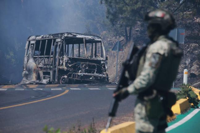 A soldier stands guard by a charred vehicle after it was set on fire in Cointzio, Michoacán state, Mexico, February 22, following the death of the leader of the Jalisco New Generation Cartel, Nemesio Oseguera, also known as ‘El Mencho’.